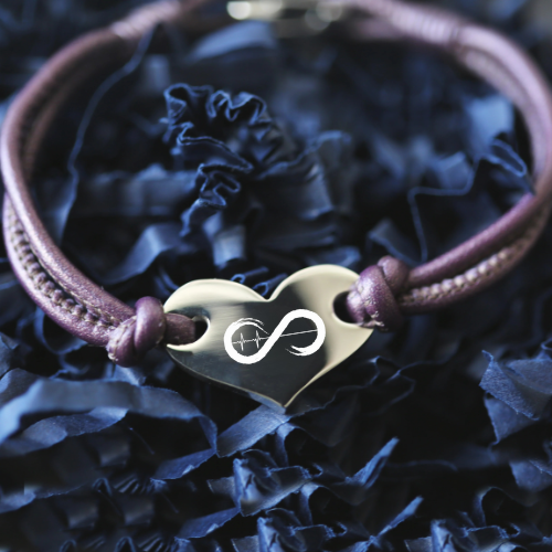 Bracelet with heart-shaped silver charm on a dark blue fabric background