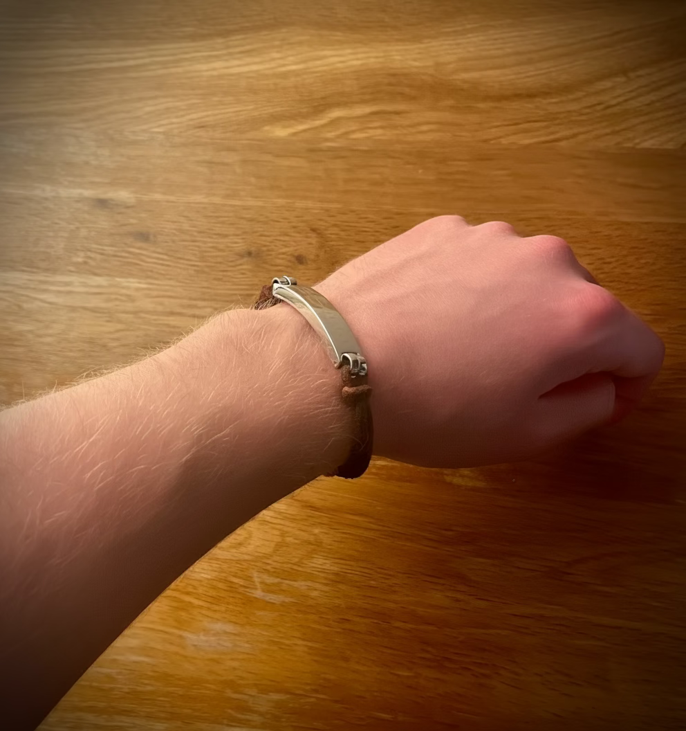 Hand wearing a bracelet on a wooden surface