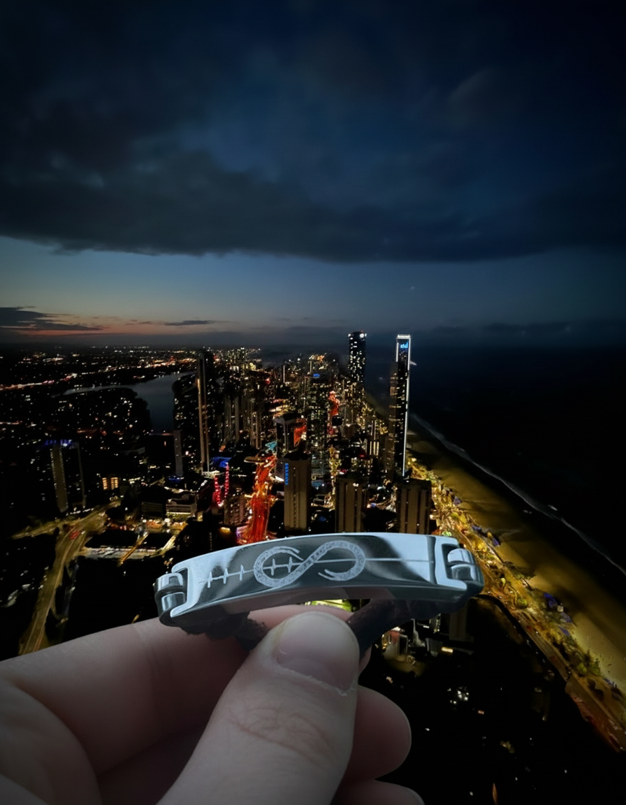 Hand holding bracelet with city at night in the background.